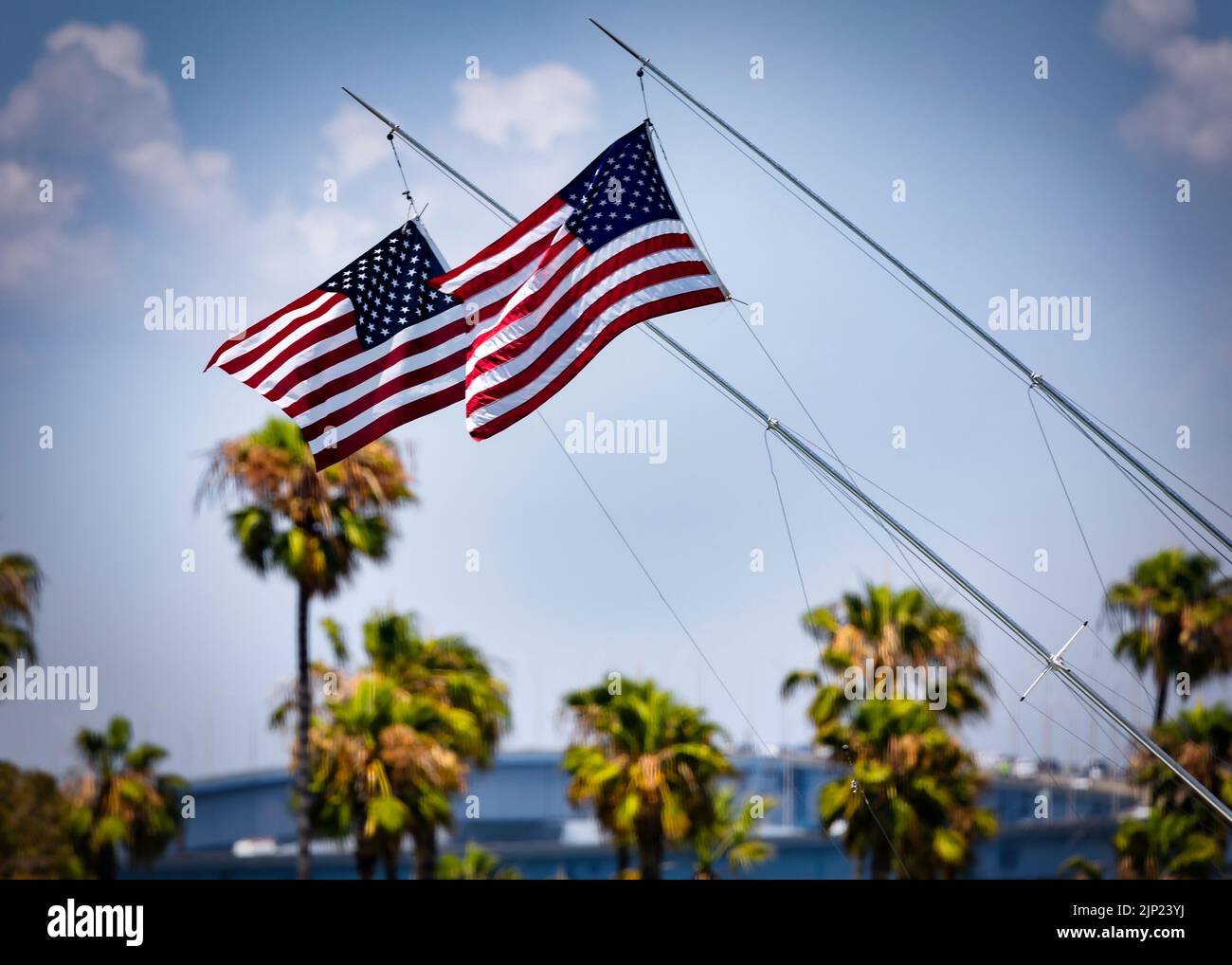 Zwei amerikanische Flaggen fliegen auf einem Segelboot, das im Wind weht, in der Glorietta Bay in Coronado, Kalifornien. Stockfoto