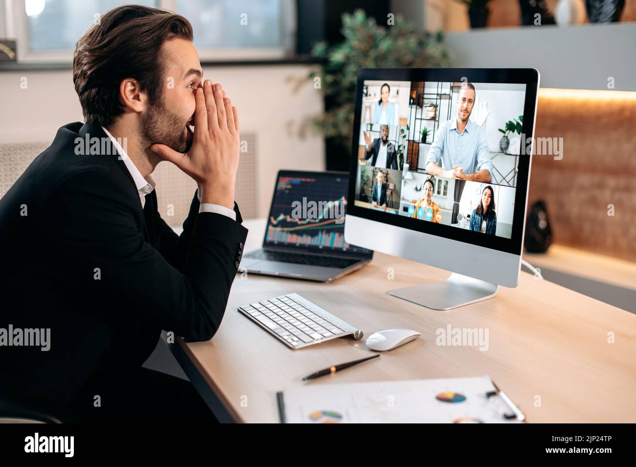 Videokonferenzen im Büro. Erfolgreicher, positiver kaukasischer Geschäftsmann in einem Anzug, sitzt an einem Arbeitsplatz, verhandelt mit Partnern per Videoanruf, diskutiert neues Projekt, Kooperationsbedingungen Stockfoto