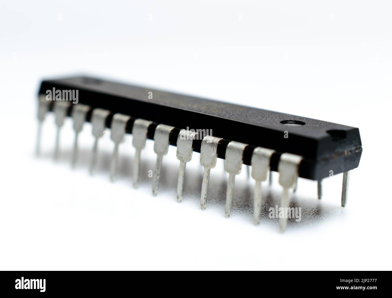 Schwarzer Mikrochip mit Metallbeinen auf weißem Hintergrund. Mikroschaltung, Silizium-Chip. Makrofoto. Teil einer Hauptplatine des Computers. Stockfoto