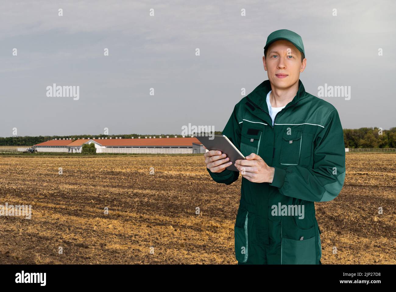 Landwirt mit Tablet-Computer auf einem Hintergrund der modernen Milchviehbetrieb Stockfoto