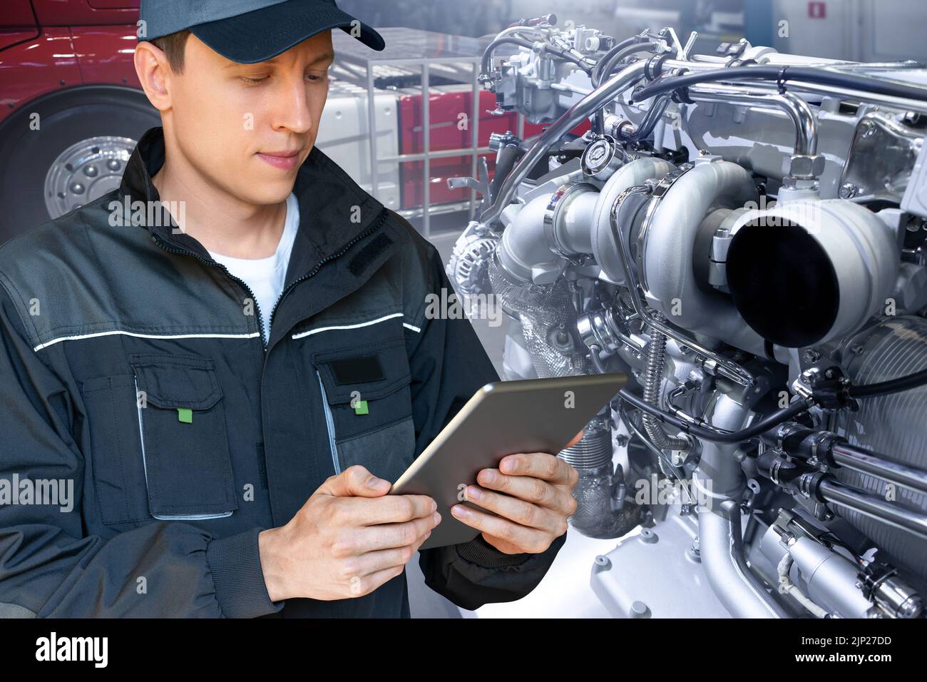 Mechaniker, der den LKW-Motor in der Garage mit einem digitalen Tablet repariert Stockfoto