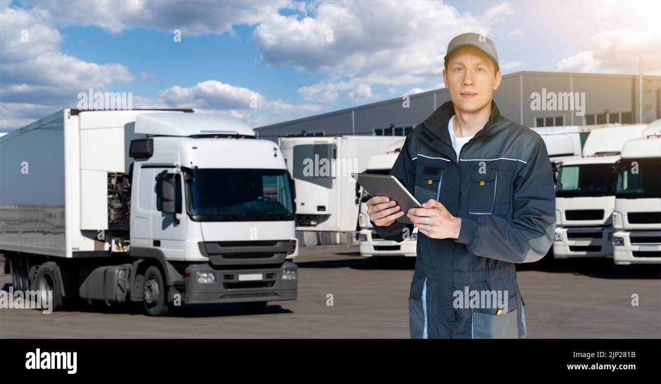Manager mit einem digitalen Tablet auf dem Hintergrund von LKWs. Flottenmanagement Stockfoto