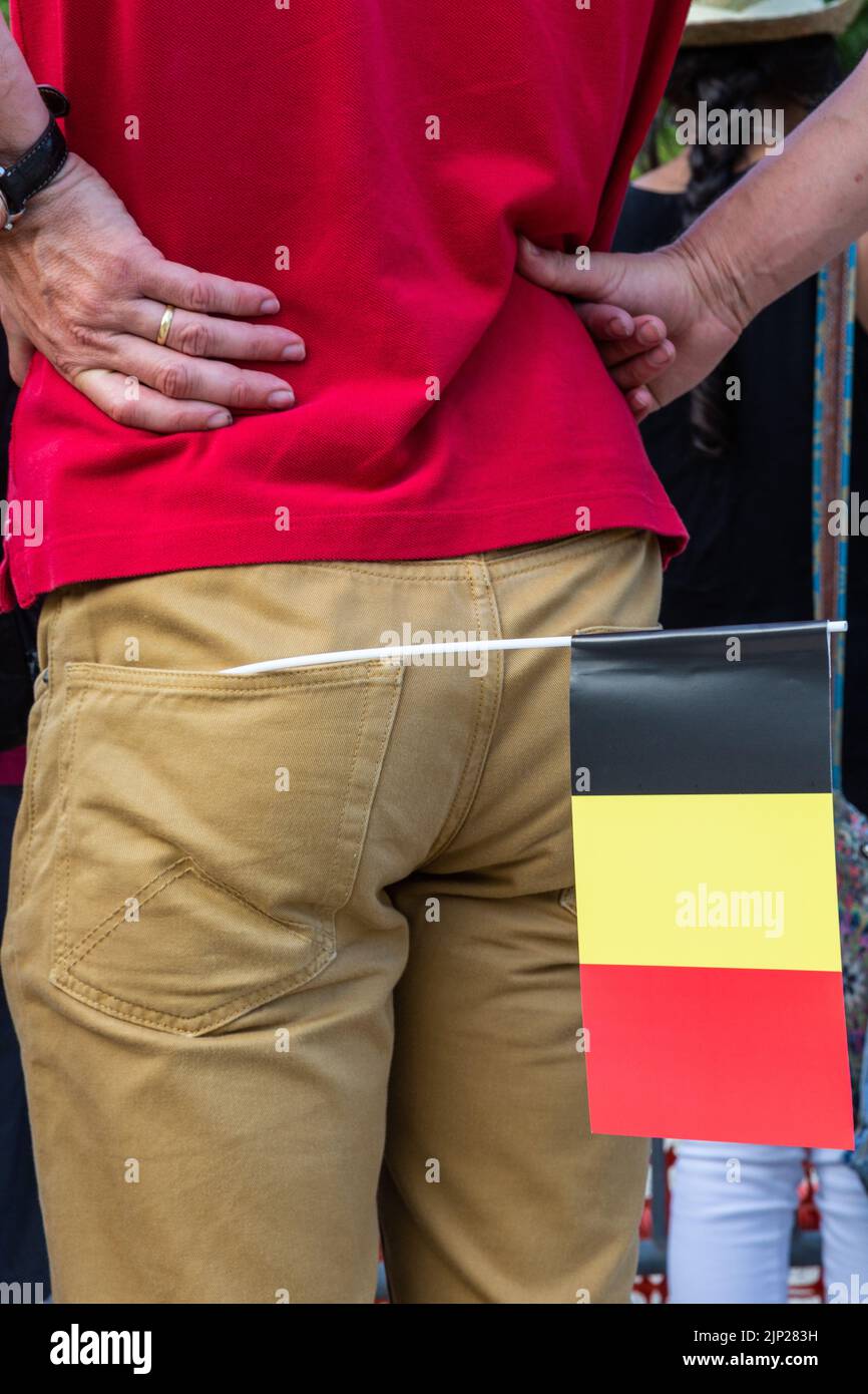 Belgische Flagge in der Gesäßtasche einer Herrenhose, rotes T-Shirt, Hände auf Hüften. Stockfoto
