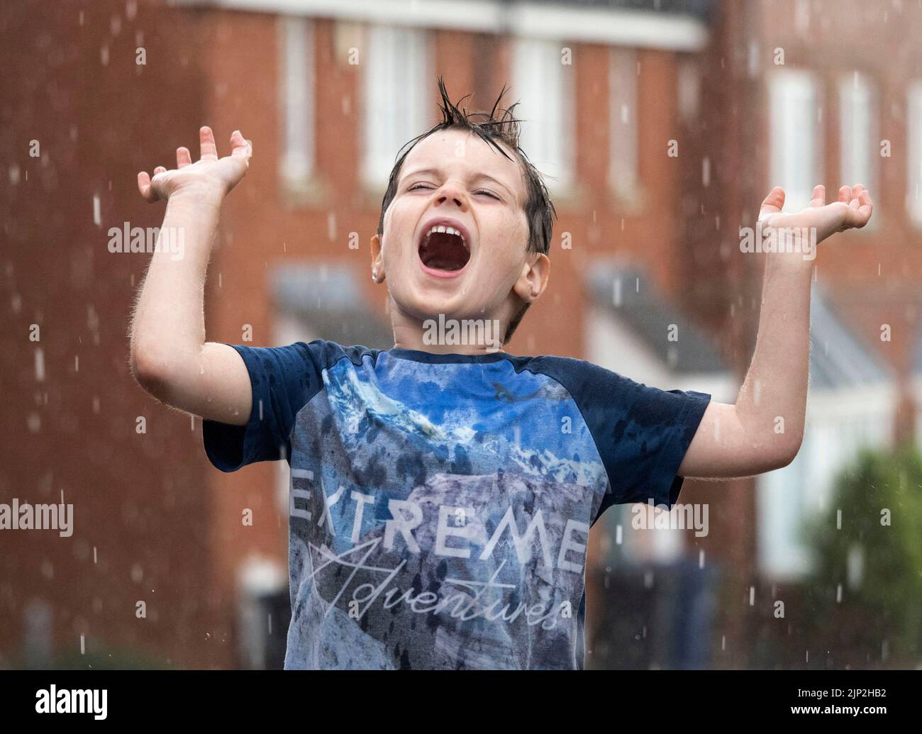 Haverhill, Suffolk, Großbritannien 15.. August 2022. Albert Mitchell, 5 Jahre alt, genießt den sintflutartigen Regen in Haverhill, Suffolk. Kredit: Headlinephoto/Alamy Live Nachrichten. Stockfoto