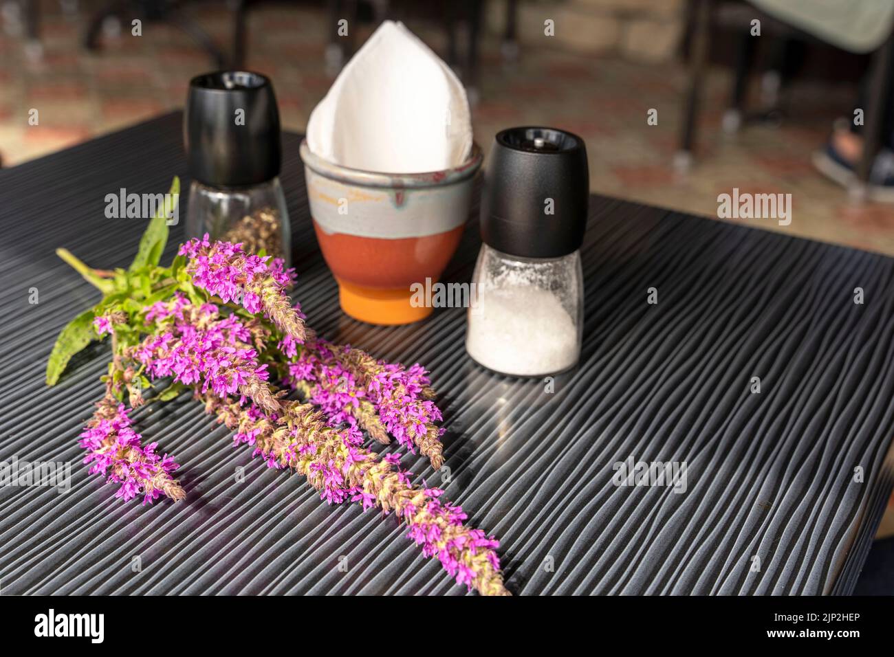 Ein Salz- und Pfefferstreuer, ein Serviettenhalter und Wildblumen auf einem Tisch Stockfoto