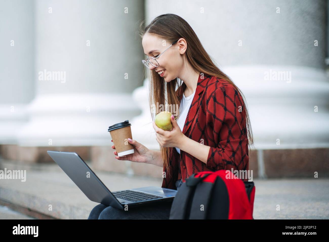 Studieren Sie Snacks, um während der Prüfungszeit die Gehirnnahrung zu überarbeiten. Happy College Student Mädchen mit Apfel und Kaffeetasse Stockfoto
