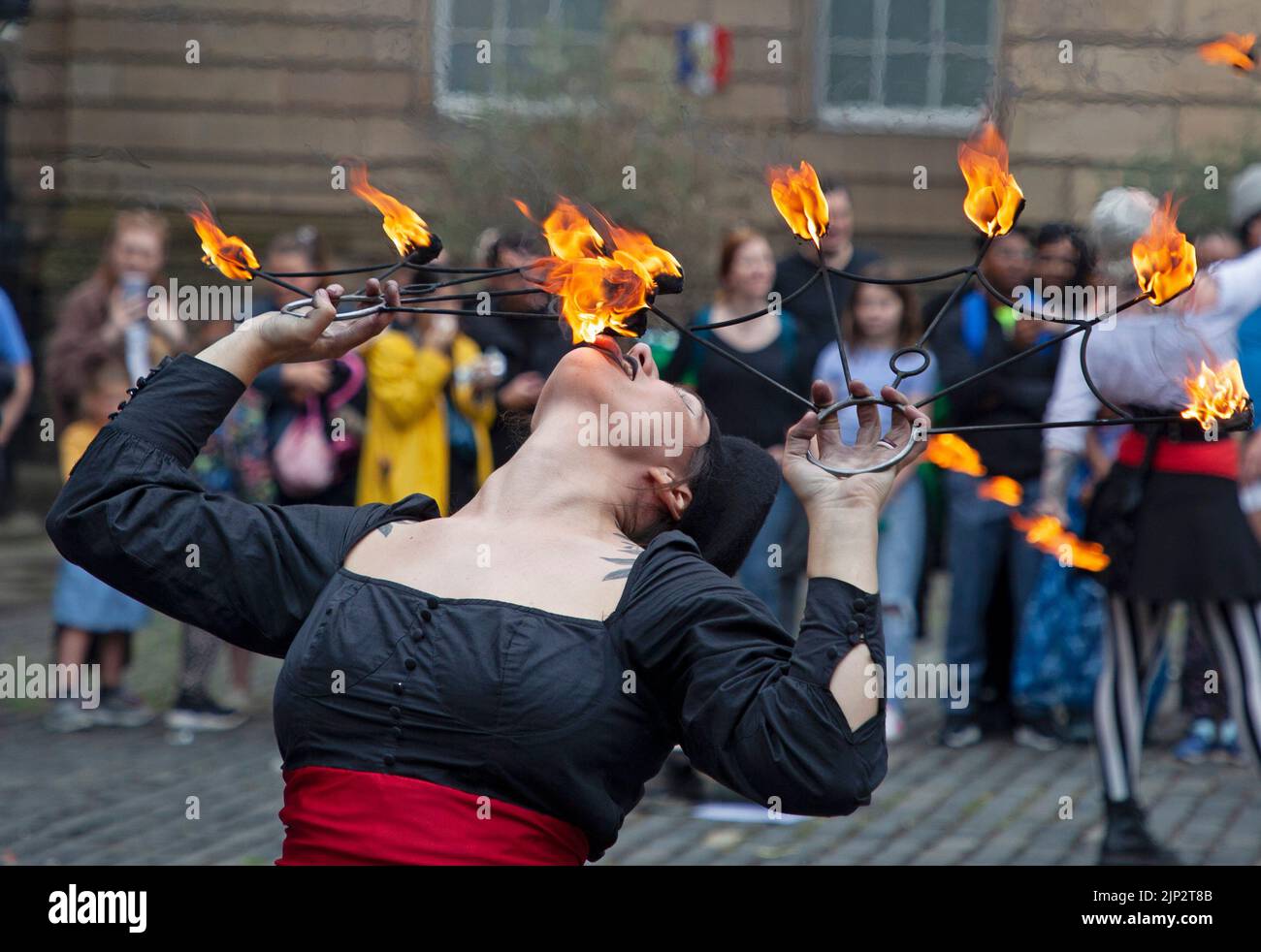 Parliament Square, Edinburgh, Schottland, Großbritannien 15.. August 2022 Edinburgh Festival Fringe, Kumpania Phoenicia Fire Show, aus den USA, Kumpania Phoenicia (Romani und Griechisch für „Phoenix Family“) unterhielt ein großes Publikum mit ihrer Feuerfackel und Feuerball-Tricks, was einem sehr langweiligen Wettertag ein willkommenes Licht gab. Im Bild: Ansley Archer isst Feuer. Quelle: Arch White/alamy Live News. Stockfoto