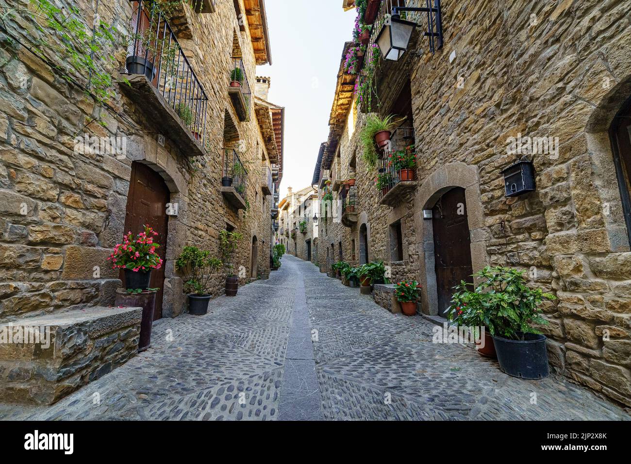 Straße einer alten mittelalterlichen Stadt mit Steinhäusern und Kopfsteinpflasterböden, Straßenlampen und einer Atmosphäre vergangener Zeiten. Ainsa, Spanien. Stockfoto