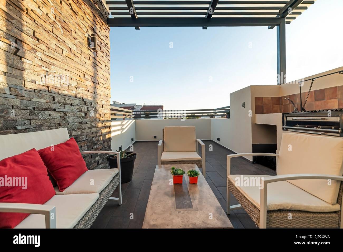 Terrasse mit Gartenmöbeln, Stein an einer Wand, können Sie den Himmel sehen, Grillplatz, Stahl Pergola Stockfoto