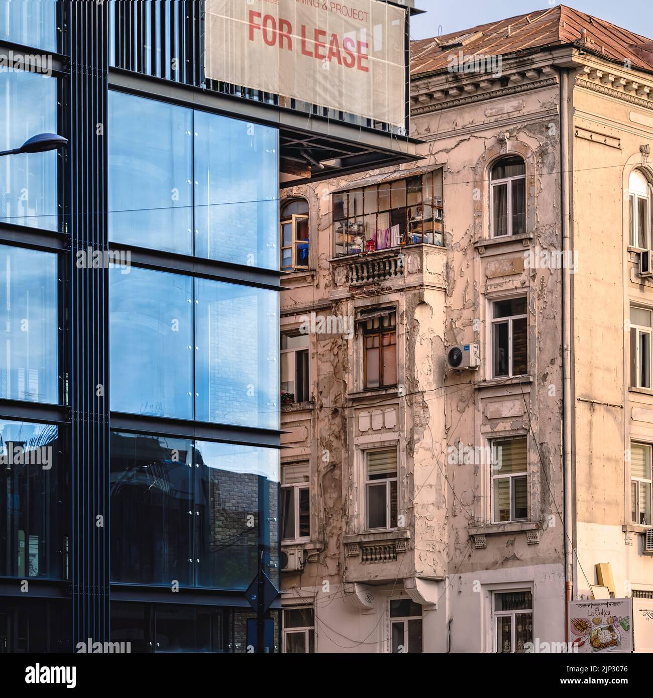Ein Kontrast zwischen einem neuen Bürogebäude und einem alten Wohngebäude im Stadtzentrum von Bukarest Stockfoto