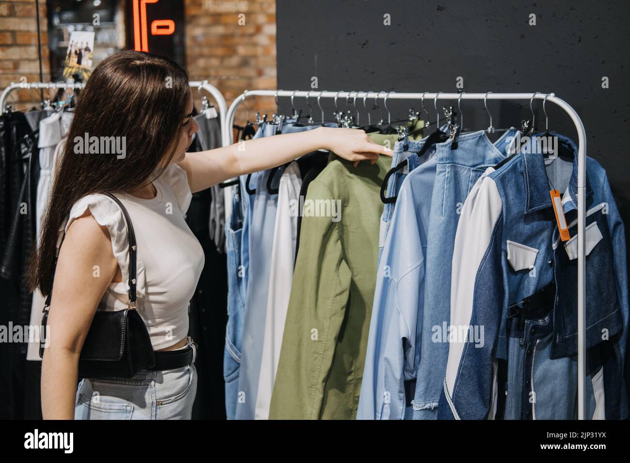 Nachhaltige Mode, langsame Mode, bewusstes Einkaufen. Junge Latina Frau, die im modernen Bekleidungsgeschäft einkaufen. Stockfoto