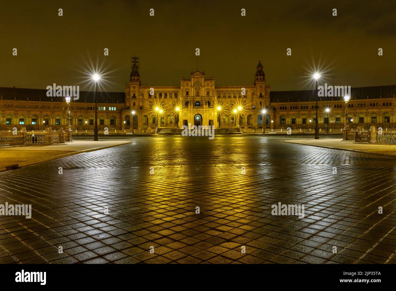 Plaza de España in Sevilla, Nachtszene nach Regen mit Langzeitbelichtung Foto und Reflexionen von Lichtern im Wasser und gepflasterten Straßen. Andalusien. Stockfoto