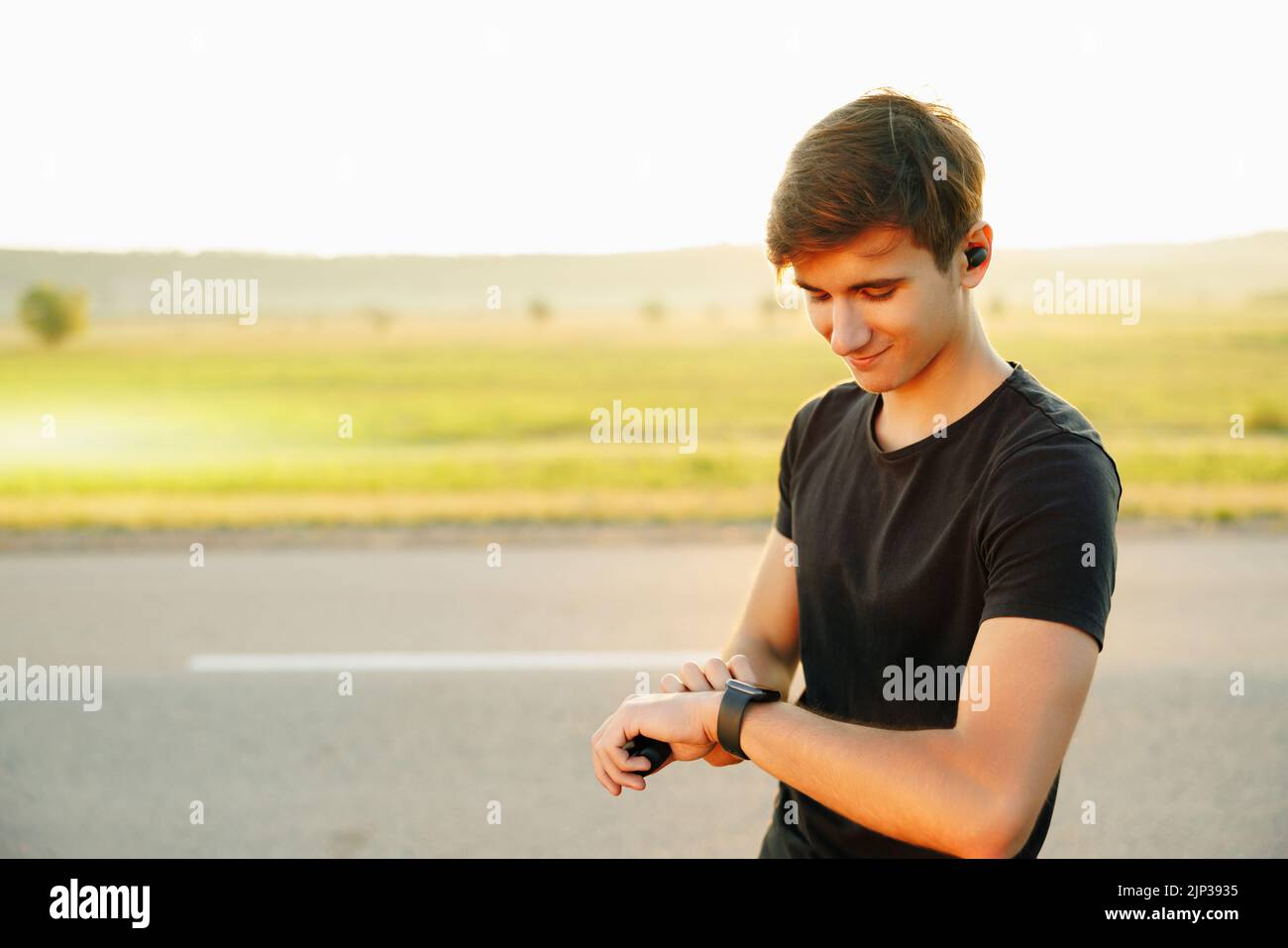 Ein glücklicher Athlet, der die Zeit betrachtet, sieht seine smarte Uhr auf der Straße Stockfoto