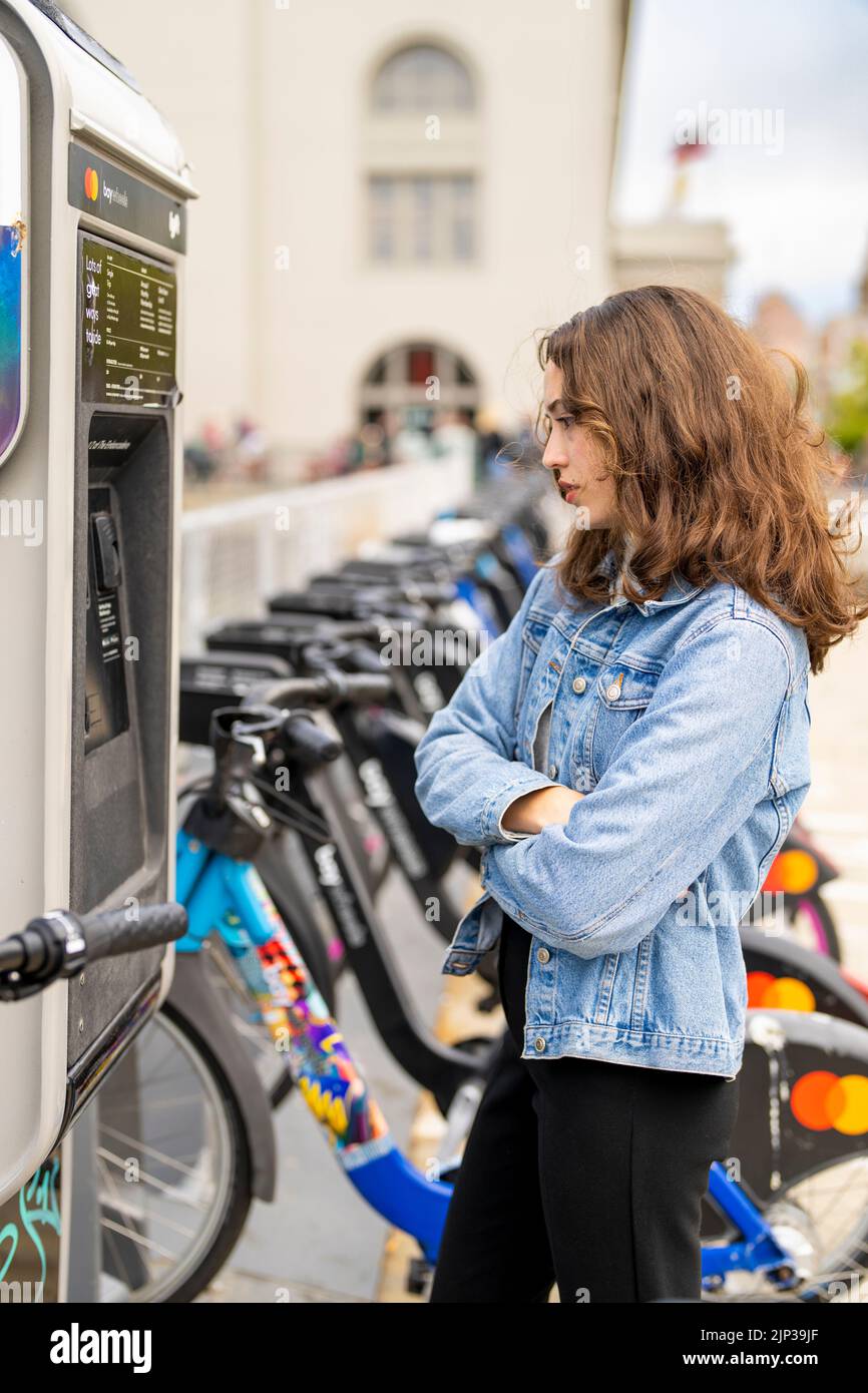 Junge Frau, die ein E-Bike mietet | Fahrradverleih | Transport | Fahrradverleih | ungestellte Porträts Stockfoto