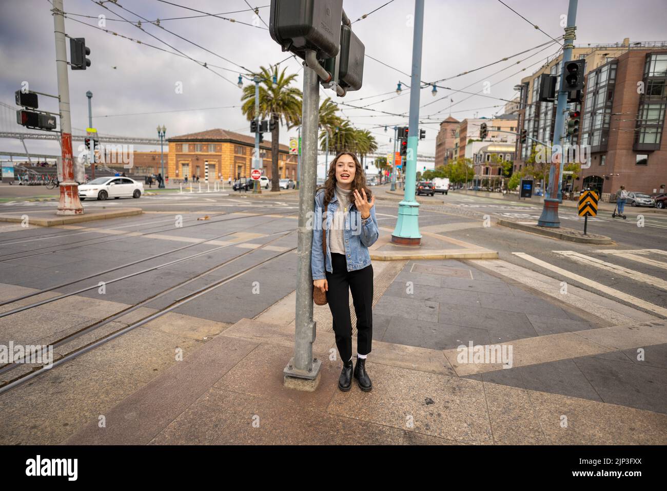 Ungeposstes Porträt einer schönen jungen Frau, die darauf wartet, eine geschäftige Downtown Street zu überqueren | Denim Jacket | San Francisco Wharf Stockfoto