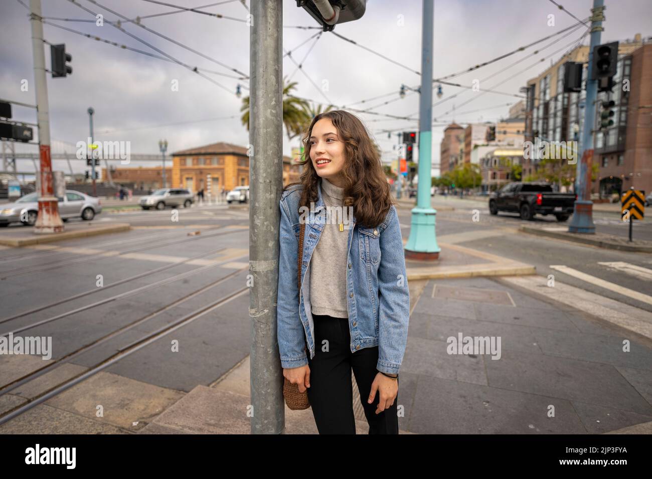 Ungeposstes Porträt einer schönen jungen Frau, die darauf wartet, eine geschäftige Downtown Street zu überqueren | Denim Jacket | San Francisco Wharf Stockfoto