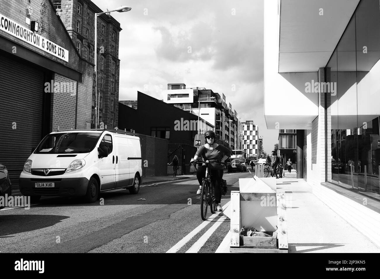 Eine Graustufe von Radfahrern, die an modernen Bürogebäuden in Dublin, Irland, vorbeifahren Stockfoto