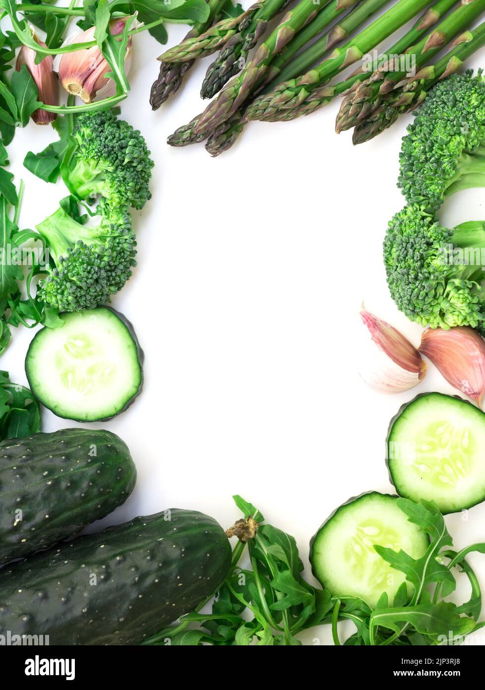 Rahmen aus grünem Gemüse Brokkoli, Rucola, Gurke, Spargel und Knoblauch auf weißem Hintergrund Stockfoto