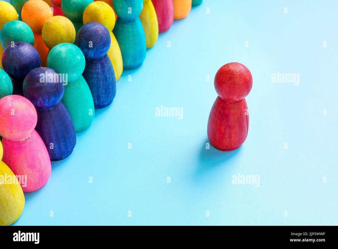 Konzept der integrativen Führung. Eine rote Figur vor einer Menge farbenfroher Figuren. Stockfoto