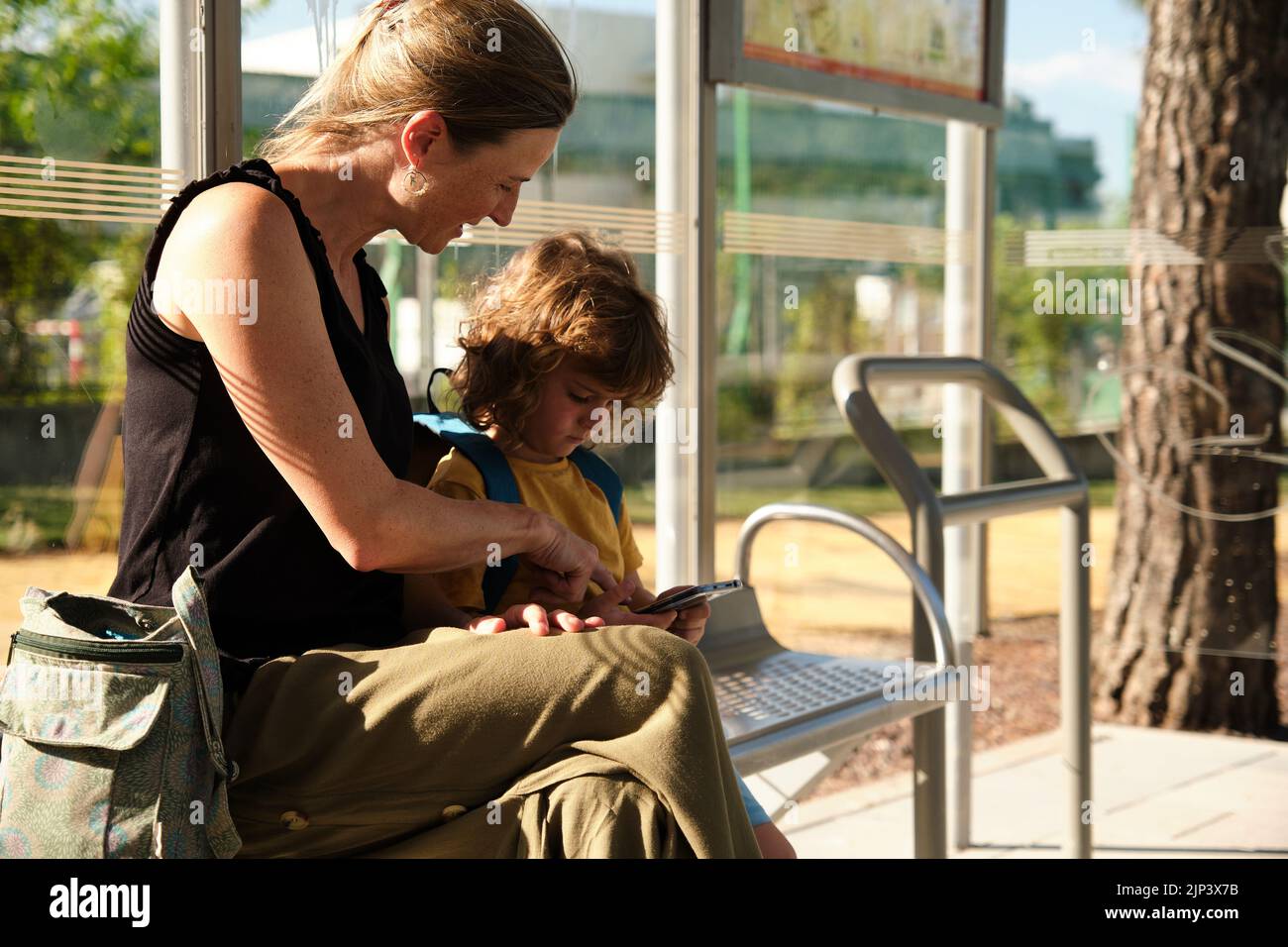 Mutter und Sohn warten an der Schulbushaltestelle Stockfoto