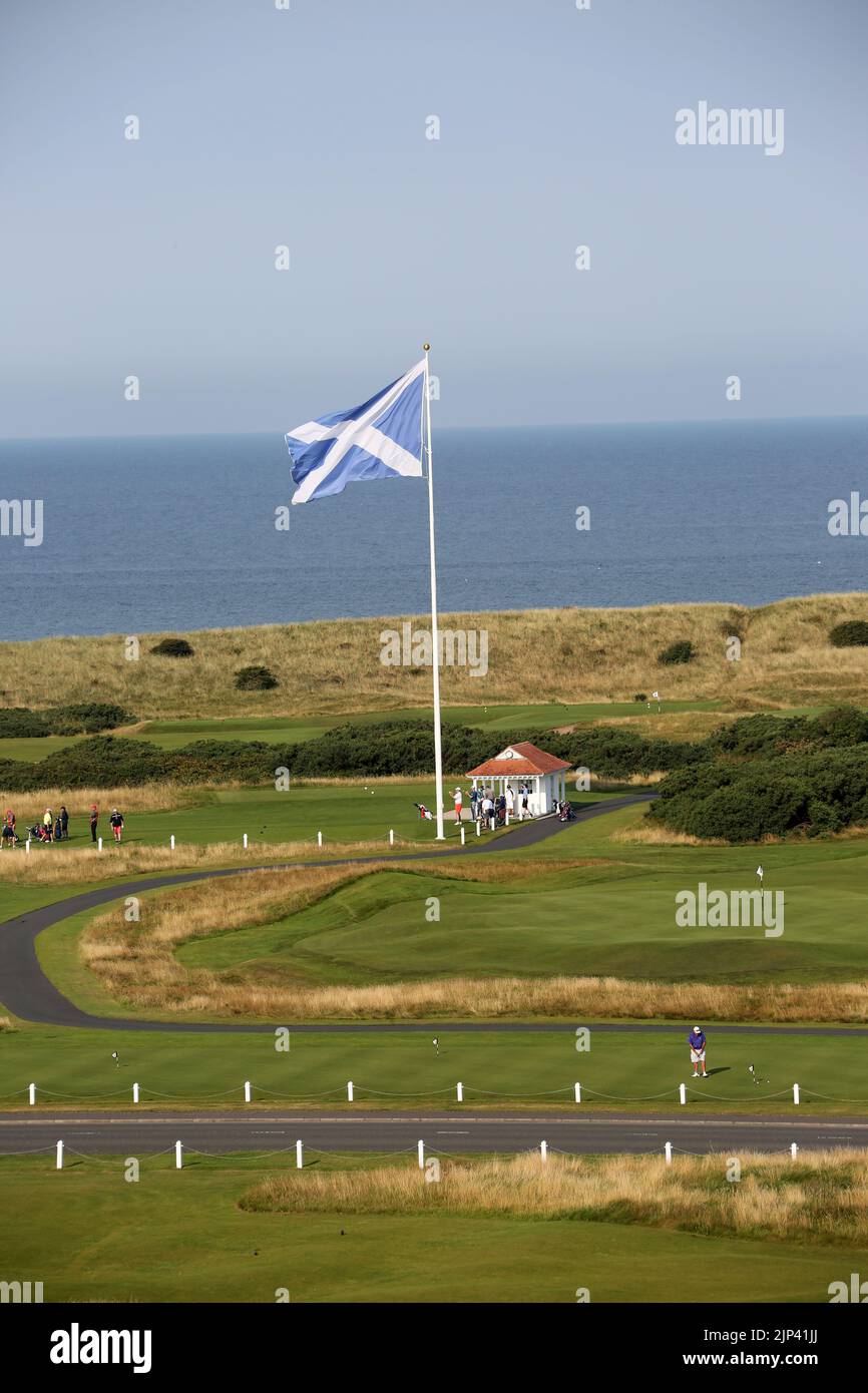 Trump Turnberry, Ayrshire, Schottland Großbritannien.eine der größten Saltire-Flaggen in Schottland dominiert die Gegend und kann von Meilen entfernt gesehen werden. Dieser Blick vom Hotel Turnberry mit der Starterhütte für den ersten Tee, Übungsgreens und das 18. Green. Ebenfalls auf dem Foto ist die ikonische große Uhr zu sehen, die den Namen Donald Trumps trägt Stockfoto