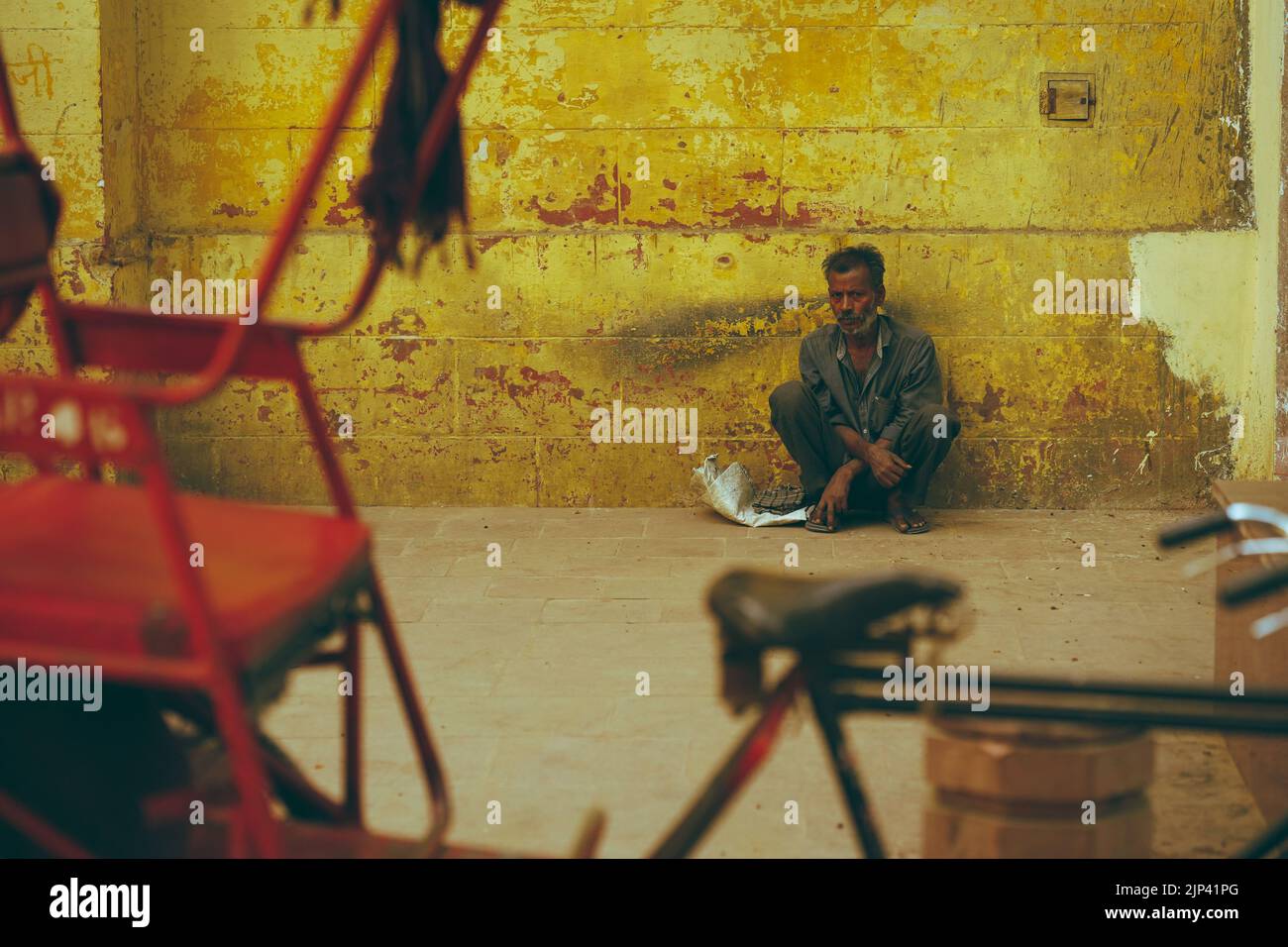 Ein armer indischer Mann, der an der Wand sitzt Stockfoto