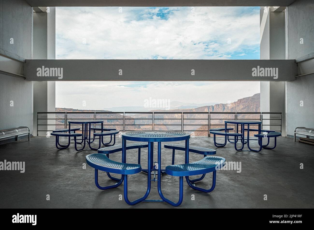 Brutalistische Betonarchitektur, großer Raum mit Blick auf eine Schlucht, blaue Essbänke. Strahl, der die Landschaft umrahmt Stockfoto