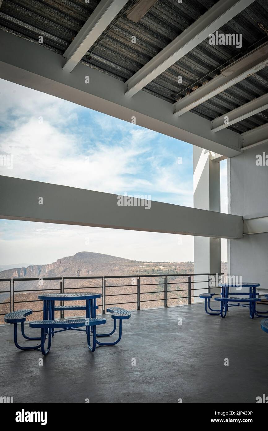 Brutalistische Betonarchitektur, großer Raum mit Blick auf eine Schlucht, blaue Essbänke. Strahl, der die Landschaft umrahmt Stockfoto