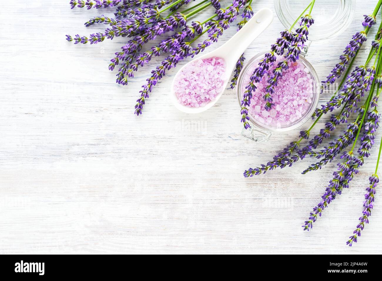 Lavendel Aroma Badesalz und Lavendelblüten auf weißem Holzhintergrund. Spa, Hautpflegekonzept. Draufsicht, Kopierbereich. Selektiver Fokus Stockfoto