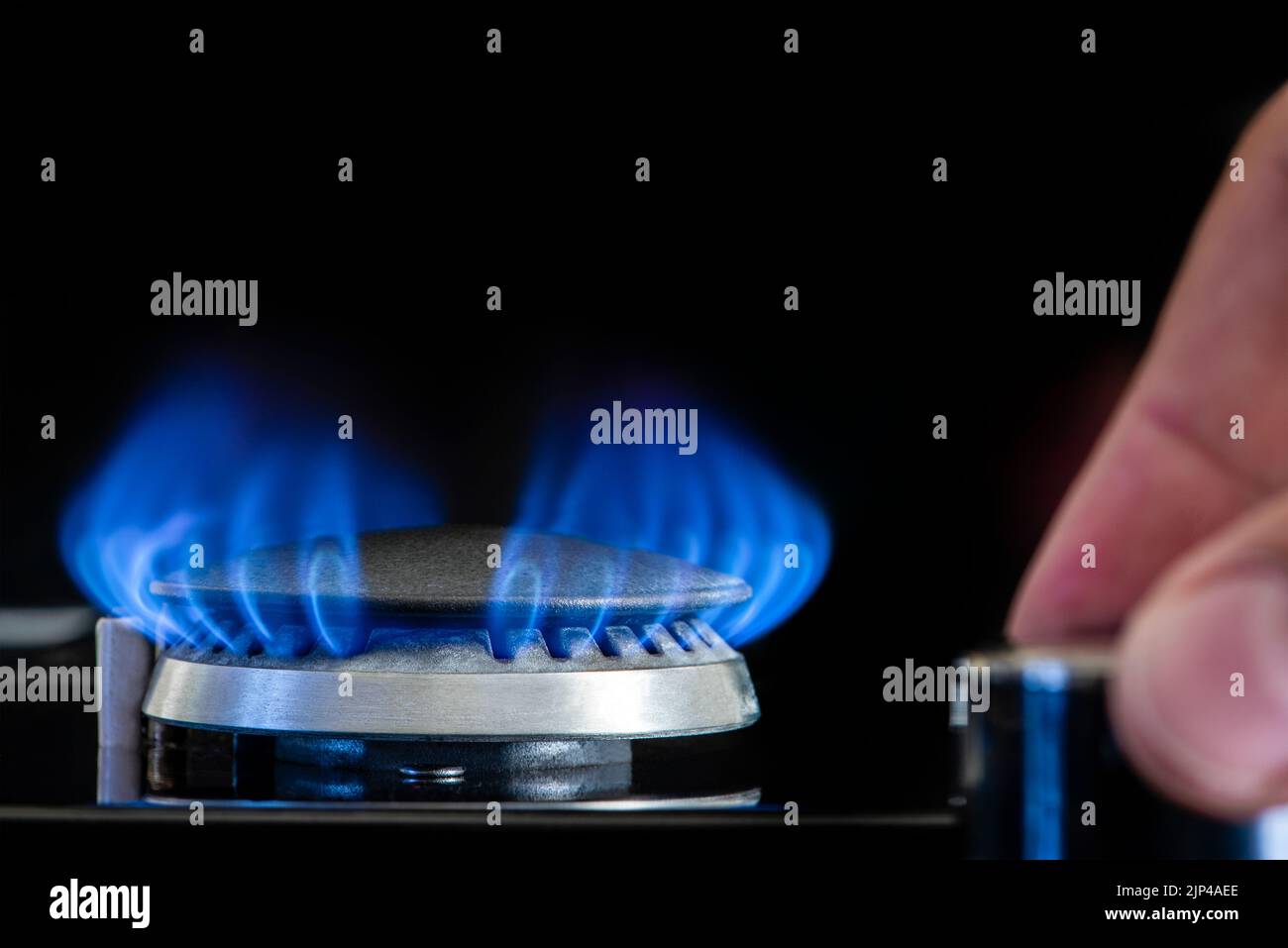 Gasherd auf schwarzem Hintergrund. Fragment eines Gas-Küchenofens mit blauer Flamme, Nahaufnahme. Energiekrisenkonzept, Anstieg des Preises oder des Gaspreises. Stockfoto