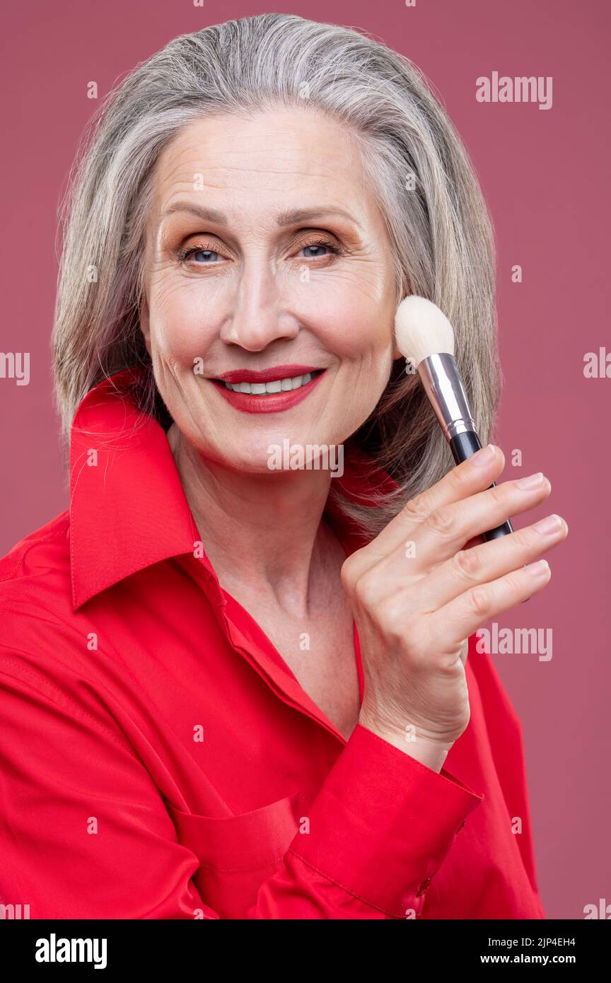 Porträt einer lächelnden Frau mit einem Gesichtsbesen Stockfoto