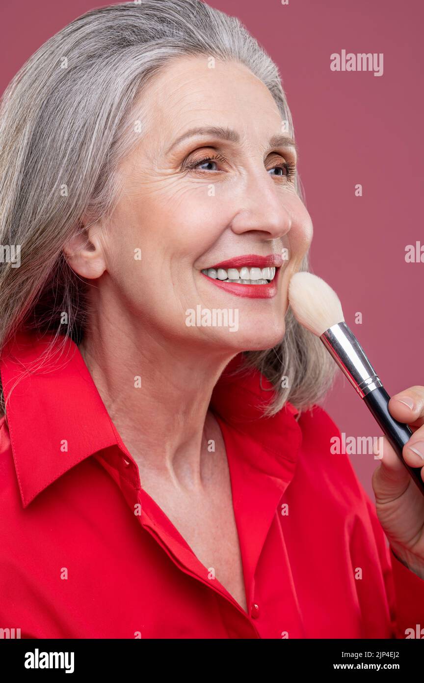 Porträt einer lächelnden Frau mit einem Gesichtsbesen Stockfoto