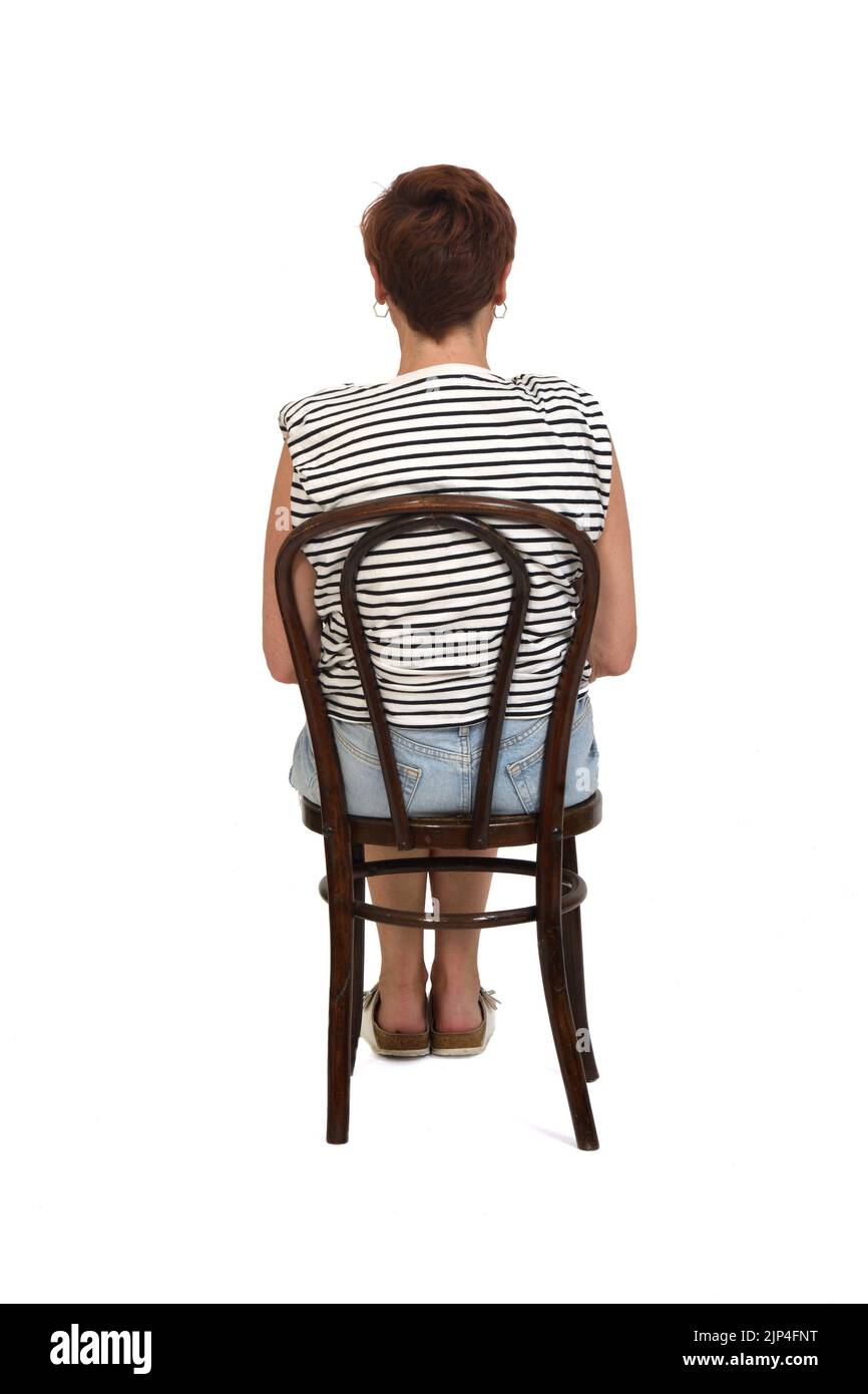 Rückansicht einer Frau mittleren Alters, die auf einem Stuhl auf weißem Hintergrund sitzt Stockfoto
