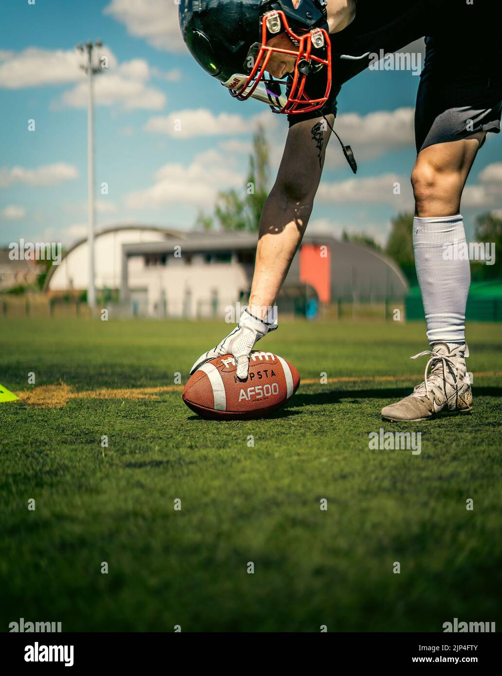 Ein amerikanischer Fußballspieler, der mit weißen Nike Handschuhen einen Kipsta-Ball auf das Synthetikfeld legt Stockfoto
