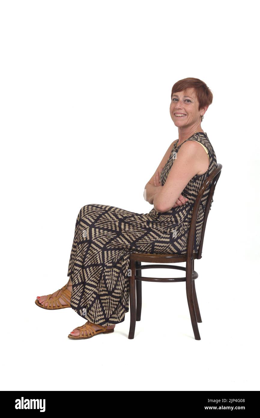 Seitenansicht einer Frau mittleren Alters, die auf einem Stuhl sitzt und die Arme auf weißem Hintergrund gekreuzt sind Stockfoto