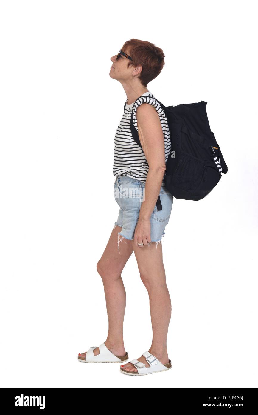 Seitenansicht einer Frau mittleren Alters an einem Sommertag mit Rucksack und Sonnenbrille auf weißem Hintergrund Stockfoto