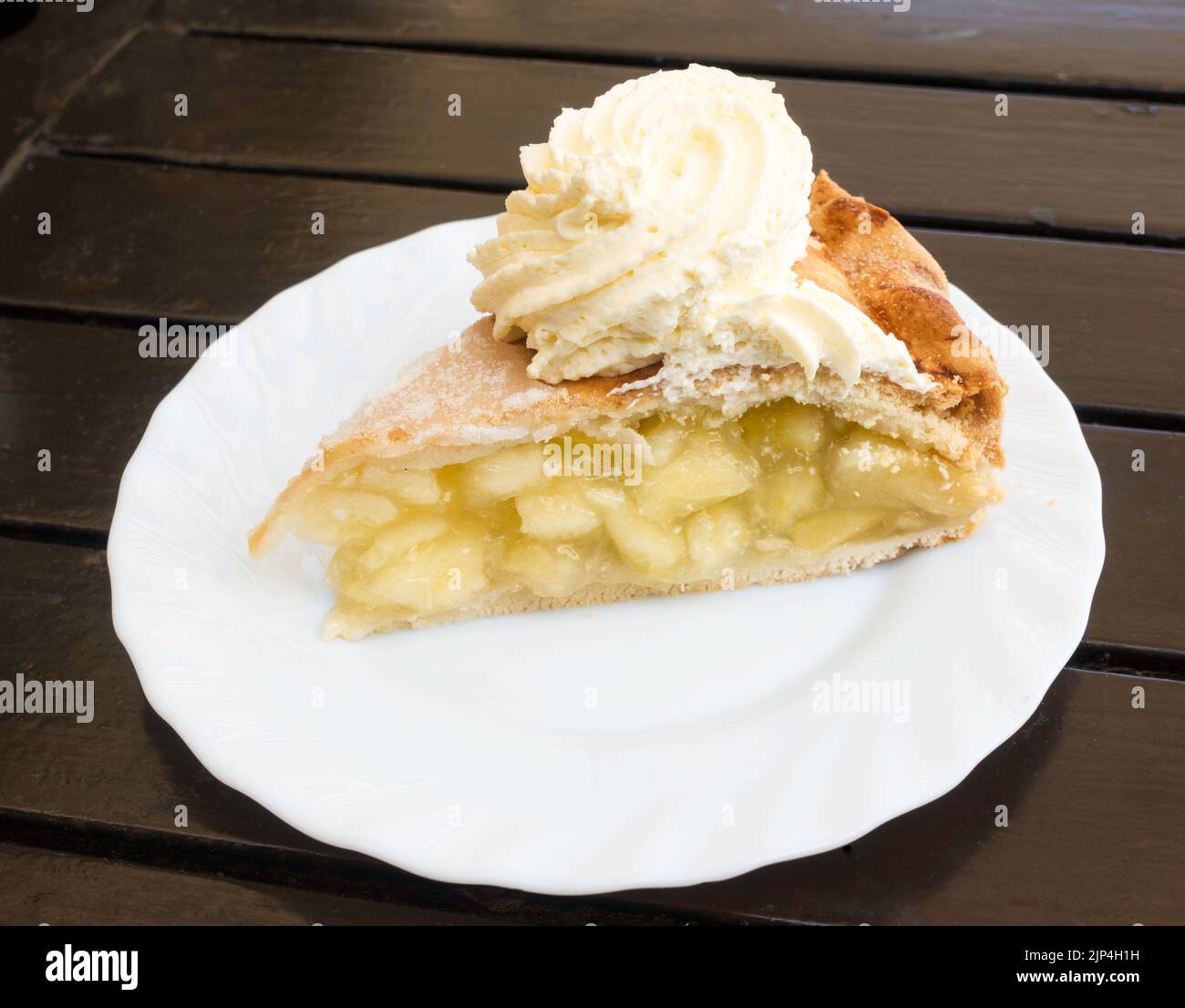 Eine Scheibe Apfelkuchen mit Creme auf einem weißen Teller. Stockfoto