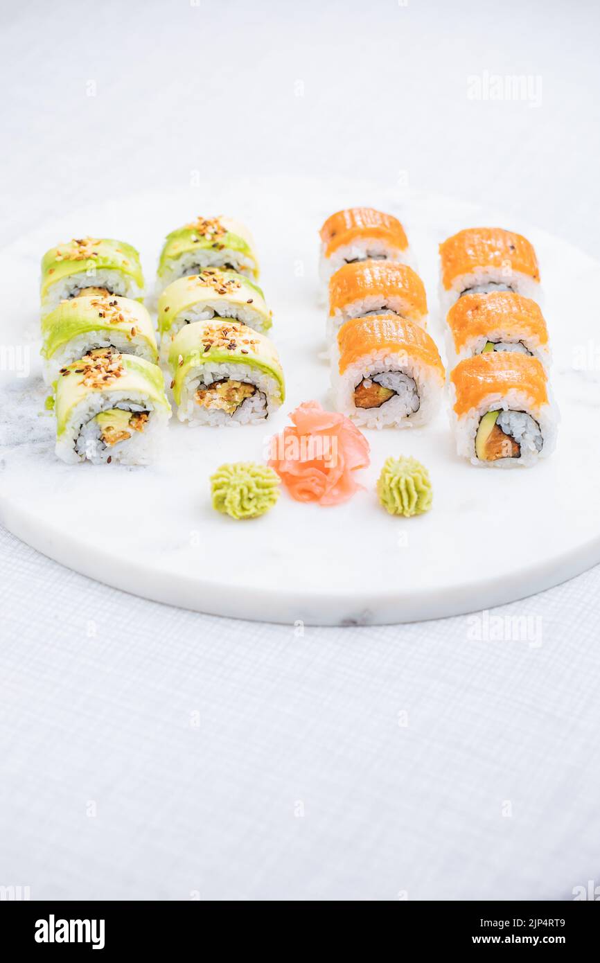 Sushi-Rollen auf Platte, heller Hintergrund. Serviert mit Wasabi und Ingwer. Verschiedene japanische Sushi. Traditionelles Essen. Stockfoto