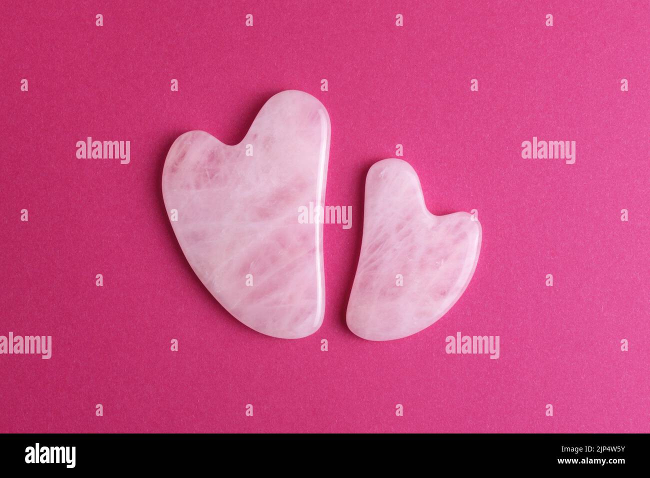Akupressur rosa transparente Gua Sha Massagegeräte unterschiedlicher Größe isoliert auf hellrosa Hintergrund. Draufsicht. Stockfoto