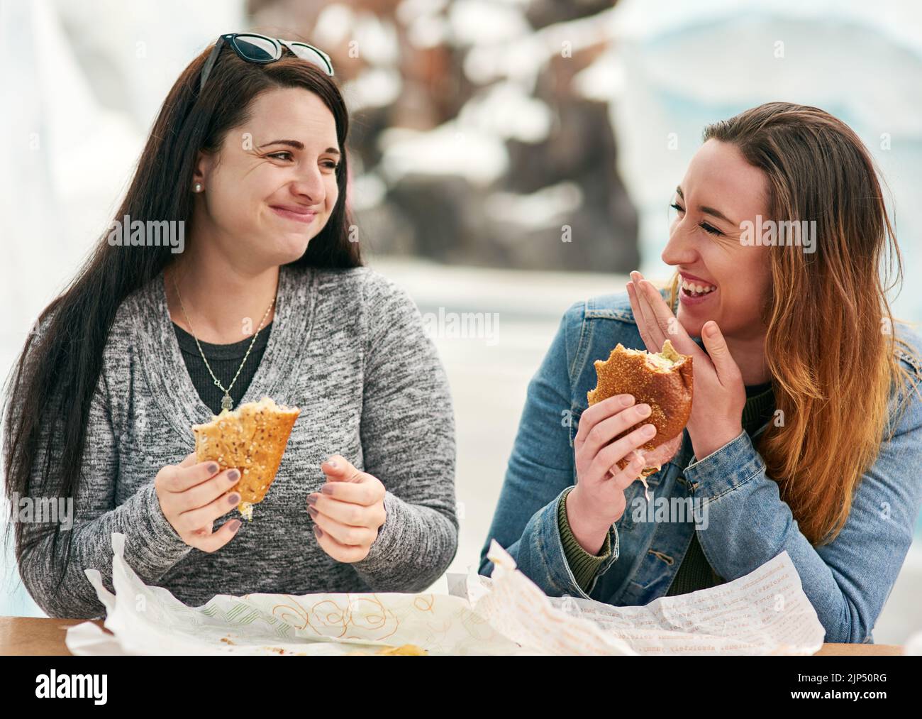 Waren hier, um zu essen und Viel Spaß., zwei weibliche beste Freunde, aßen Sandwiches in einem Vergnügungspark draußen. Stockfoto