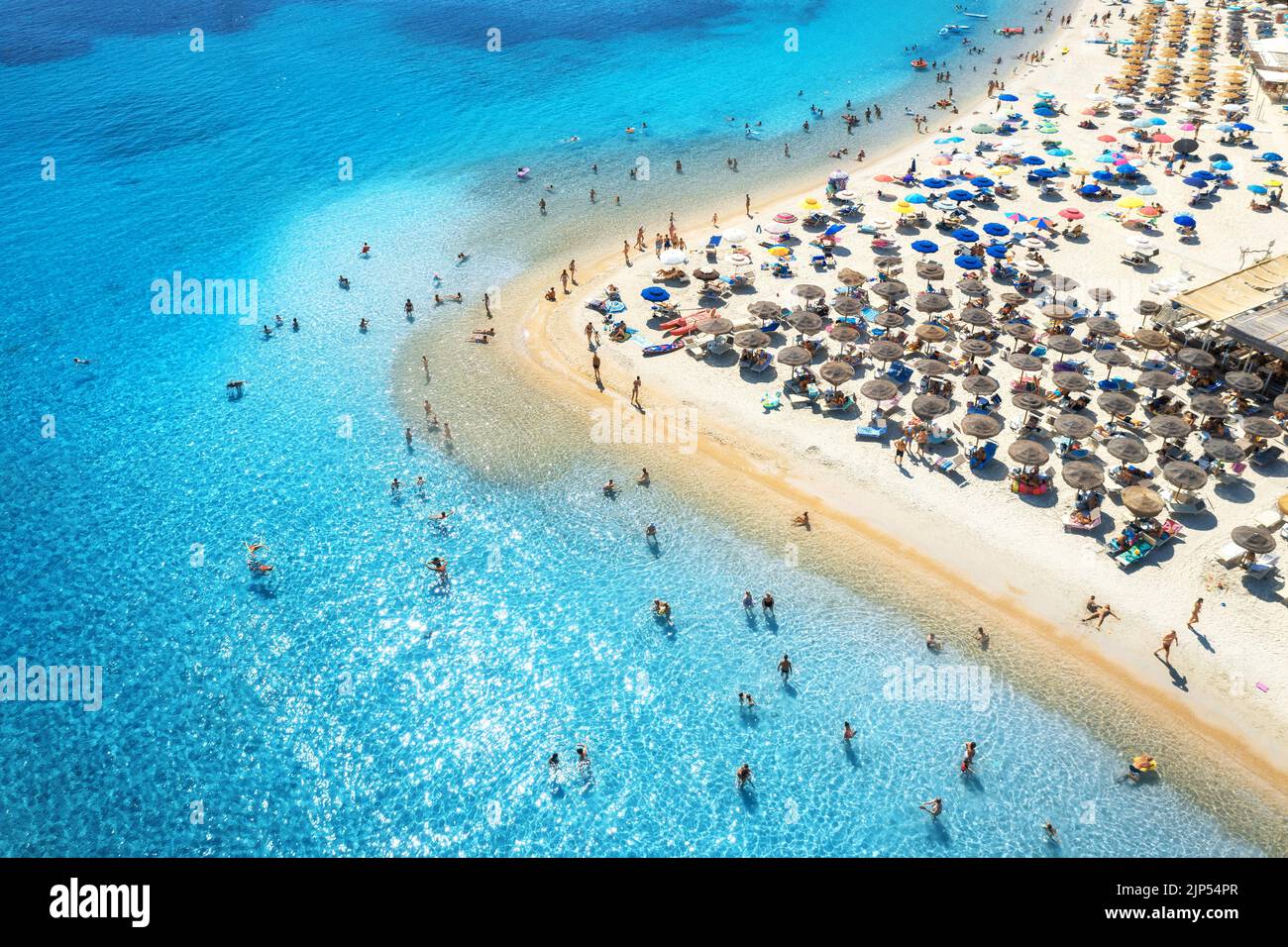 Luftaufnahme von bunten Sonnenschirmen am Sandstrand, Menschen im blauen Meer bei Sonnenuntergang im Sommer. Tuerredda Beach, Sardinien, Italien. Tropische Landschaft mit tu Stockfoto