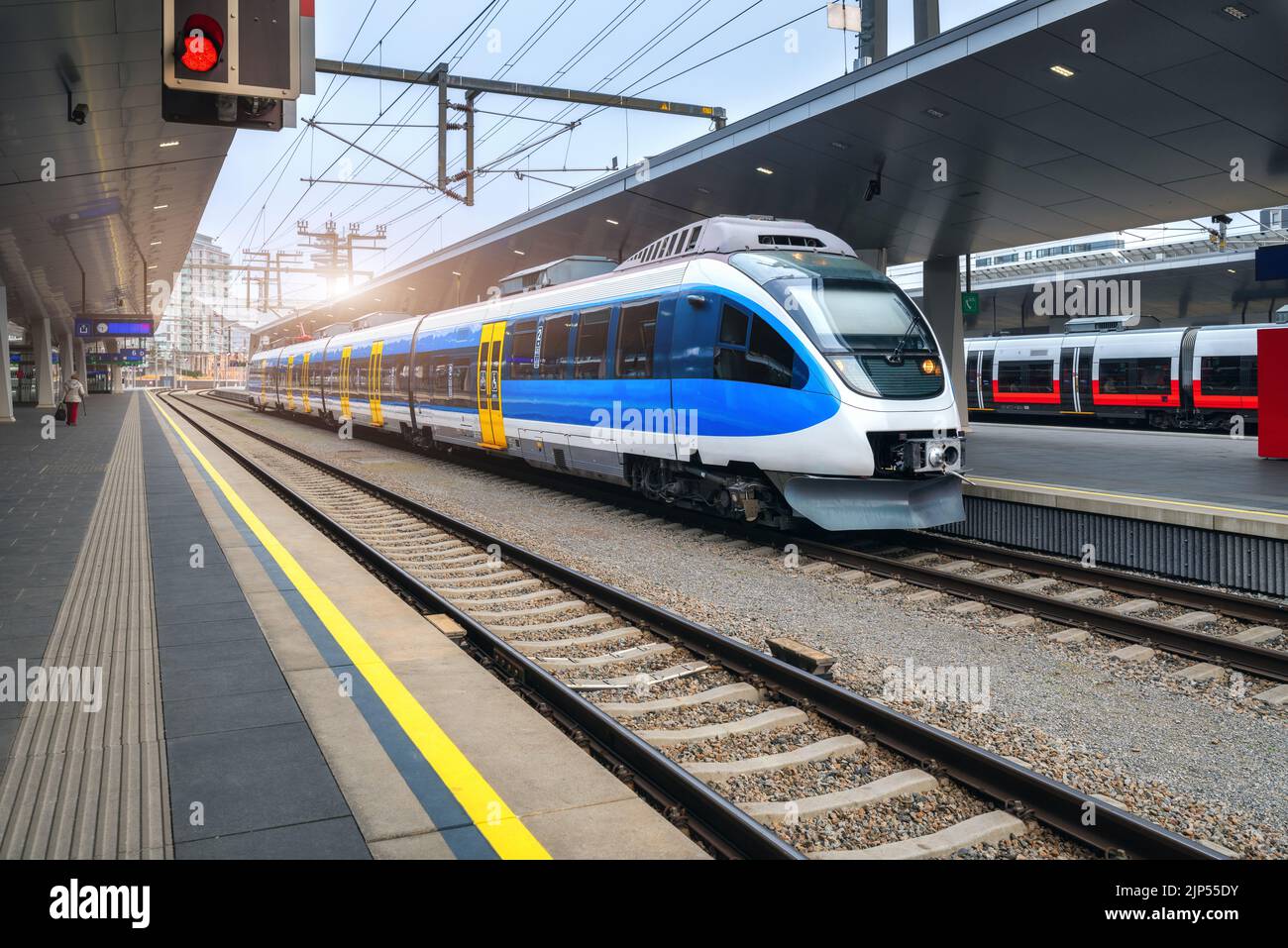 Hochgeschwindigkeitszug am Bahnhof bei Sonnenuntergang in Wien, Österreich. Schöner blauer moderner Intercity-Personenzug auf dem Bahnsteig. Eisenbahn Stockfoto