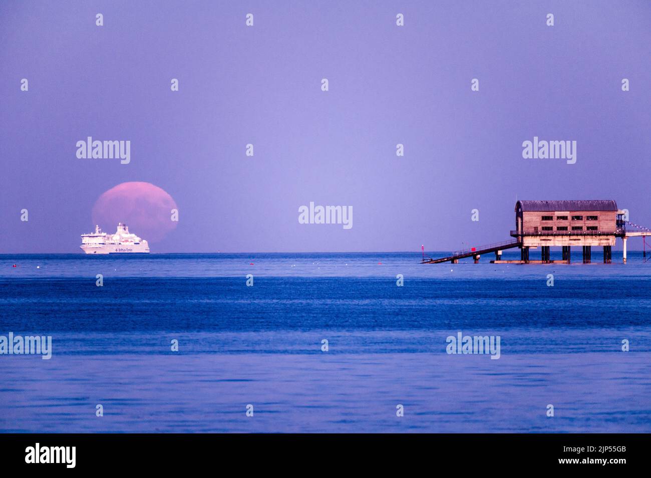 Störe Vollmond steigt über dem Bootsschuppen und Pier auf Stockfoto