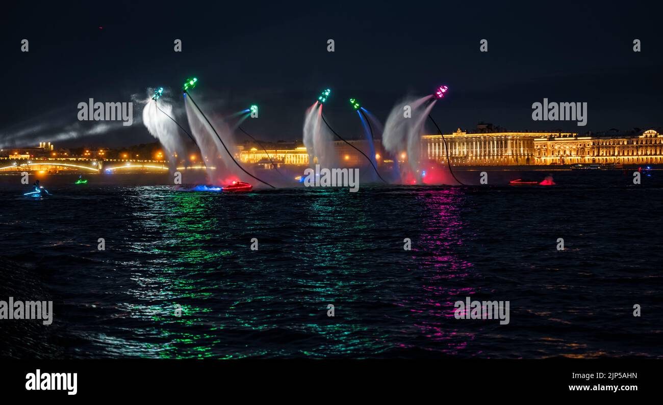 Viele Flyboarder und hell gekleidete Jet-Skifahrer führen ihre Show bei einem Urlaub im Zentrum von St. Petersburg in der Nacht, Wasseraktivitäten Stockfoto