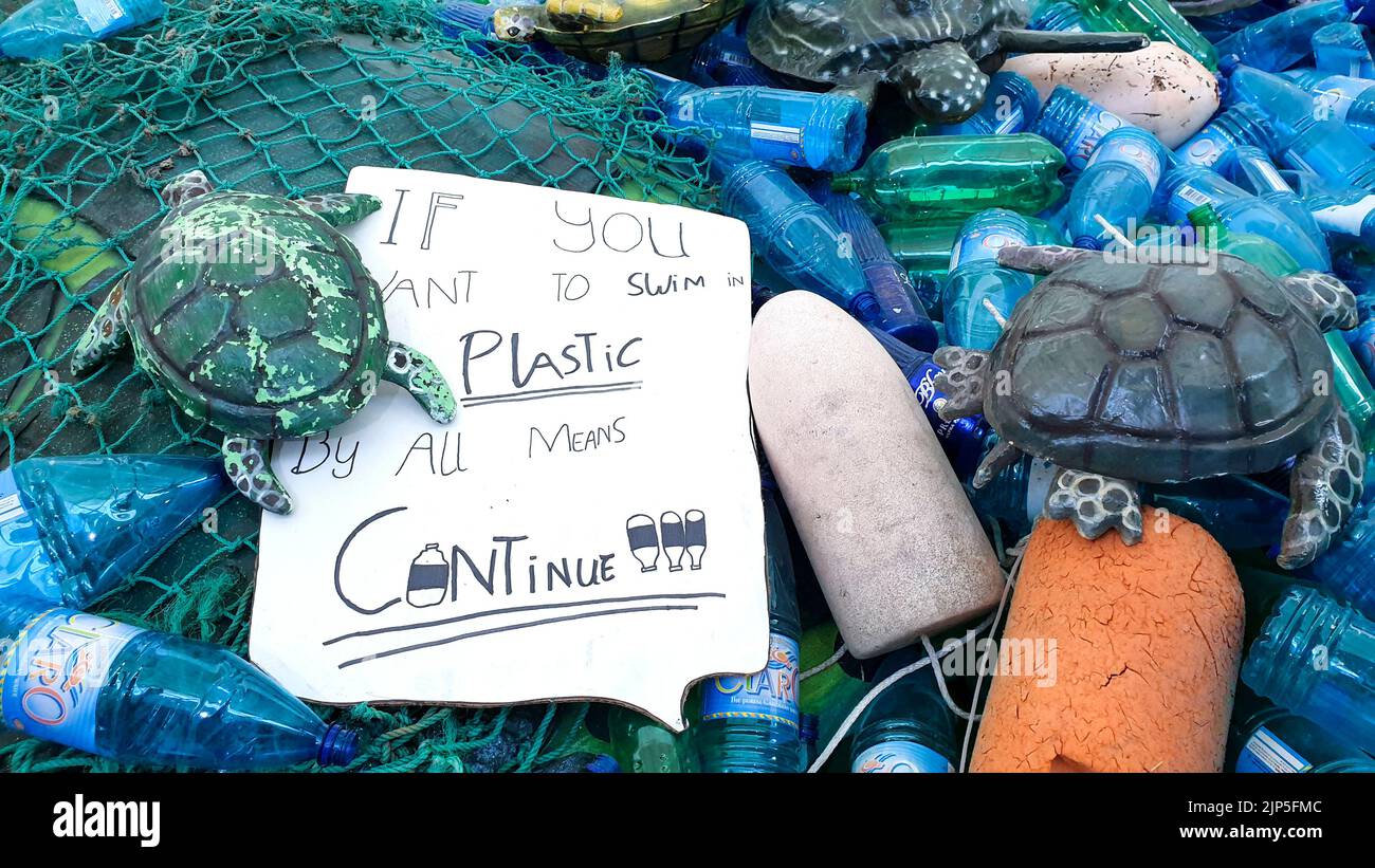 Plastikflaschen, die am Strand gewaschen wurden, Fischernetz, Schwimmwanzen und aktivierende Texte zur Reinigung von Plastikmüll. Stockfoto