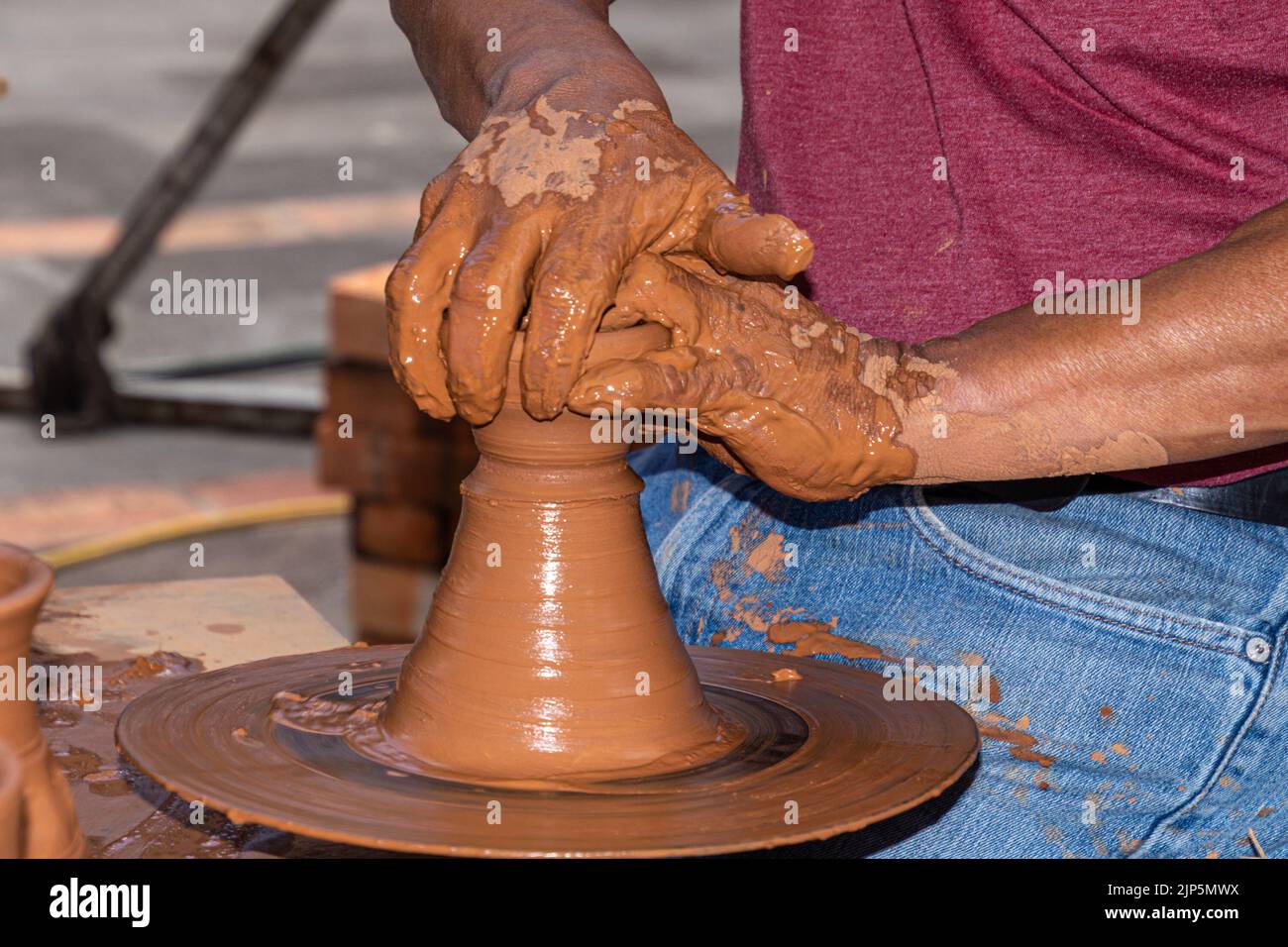Hände 0f ein Töpfermann, der an einem Töpferrad arbeitet und einen Keramiktopf aus Ton macht. Meisterklasse zum Modellieren auf einem Töpferrad. Stockfoto