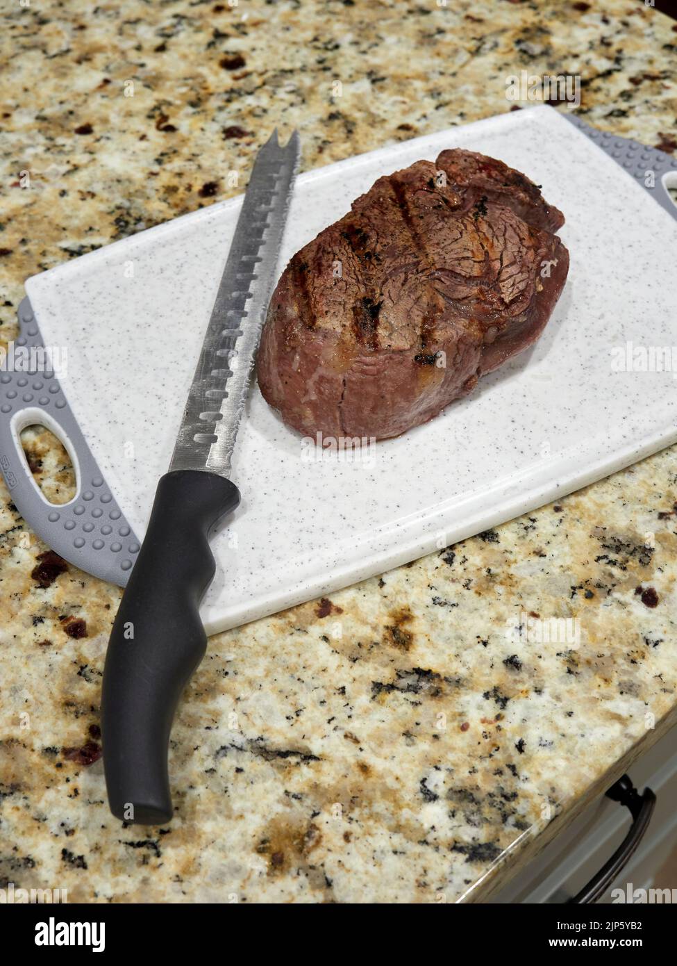 Gegrilltes oder gekochtes Filetsteak auf einem Schneidebrett mit einem Messer, das zum Mittag- oder Abendessen bereit ist. Stockfoto