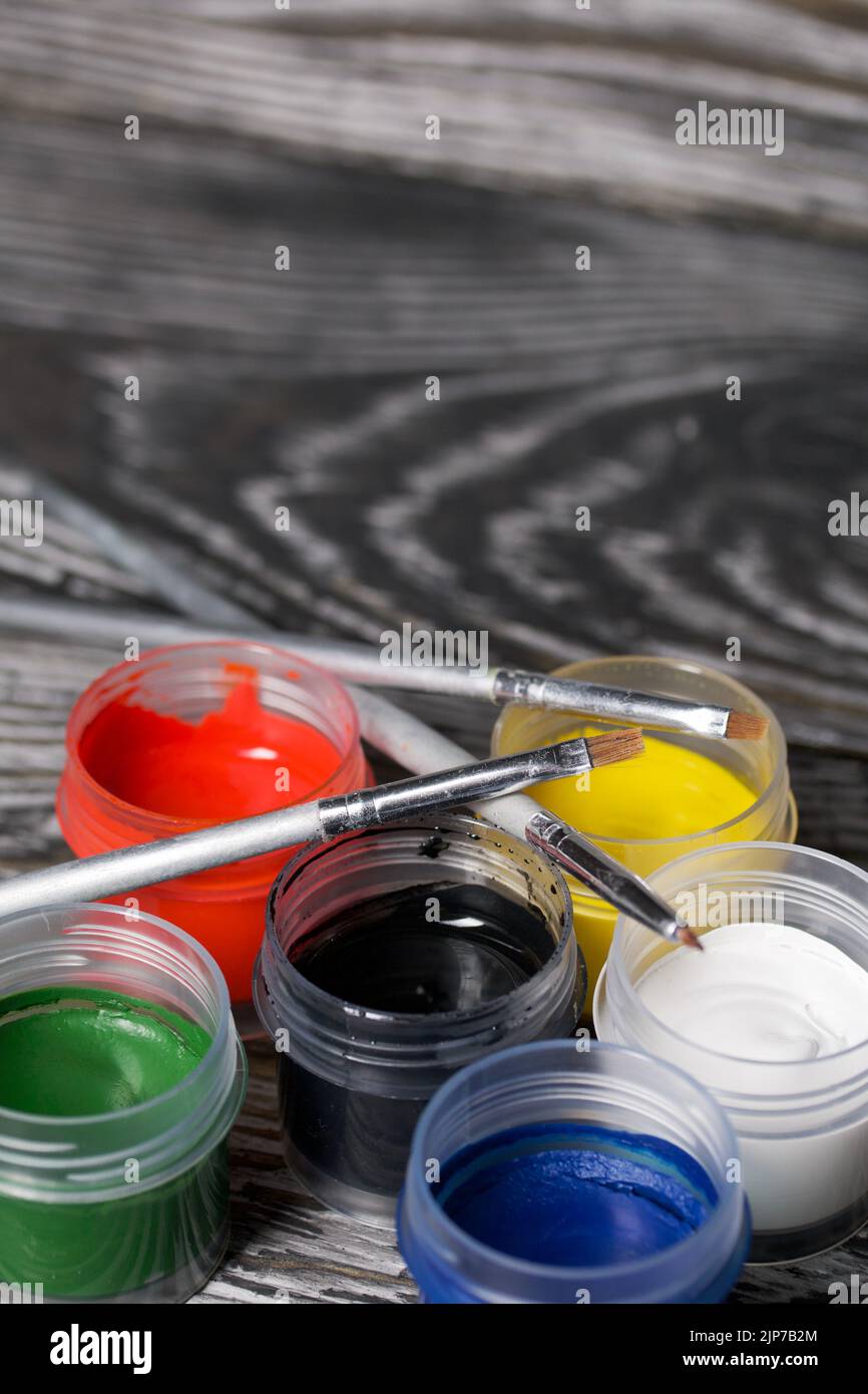 Ein Set aus Gouache und Bürsten. Farbdosen öffnen. Auf Kiefernbrettern. Nahaufnahme. Stockfoto
