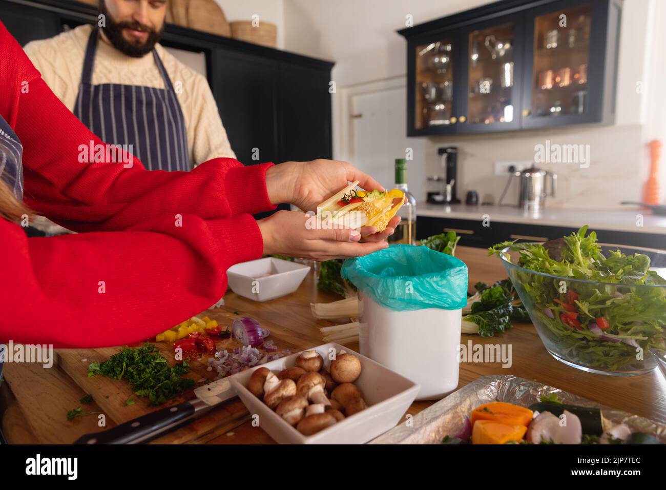 Glückliches kaukasisches Paar, das Essen in der Küche zubereitet und Gemüsereste kompostiert Stockfoto