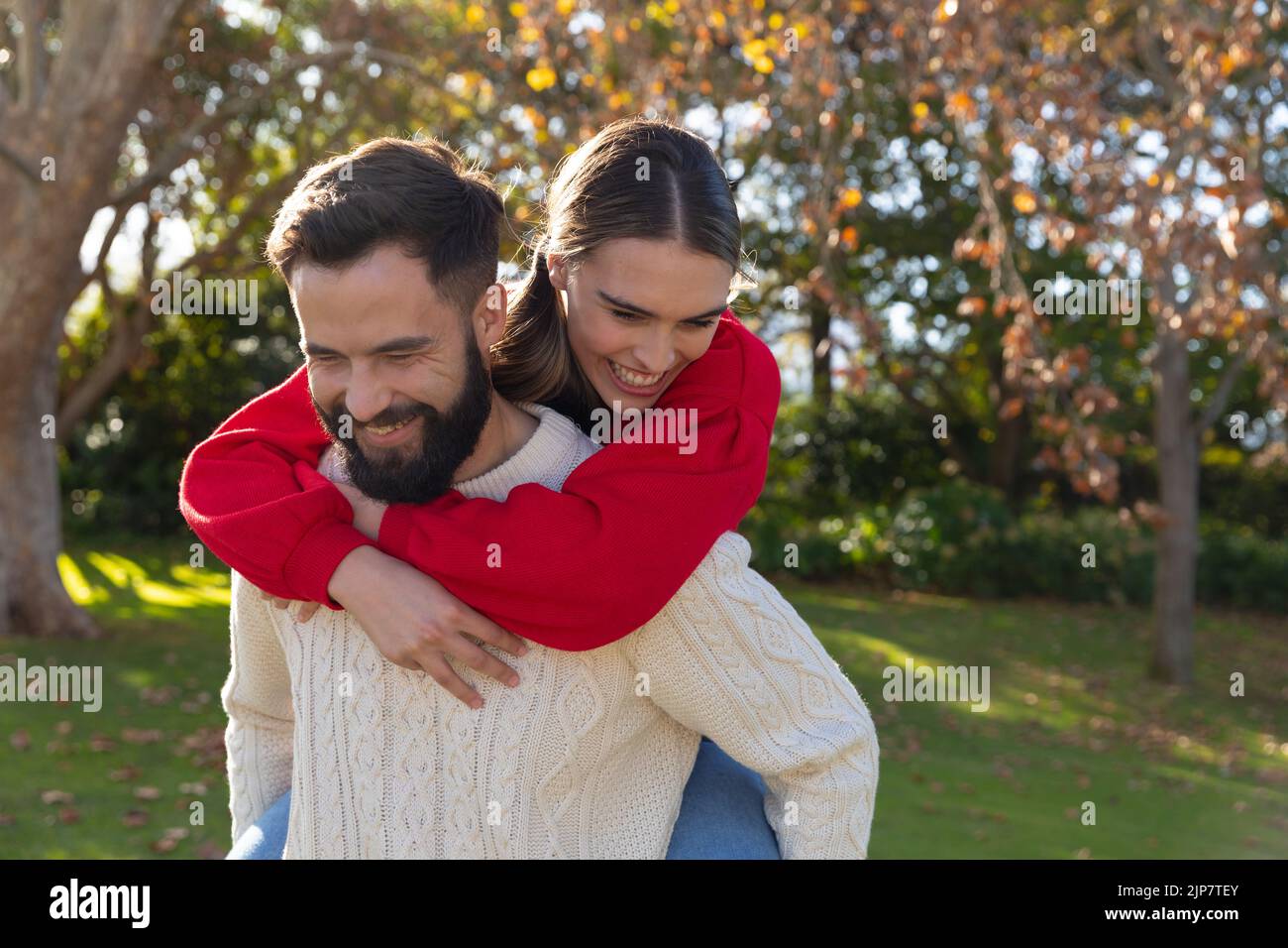Glückliches kaukasisches Paar mit Spaß Huckepack in sonnigen Herbstgarten Stockfoto